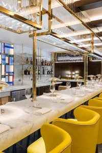 Detail of overhead bar rack in the Brasserie created from V-Grooved PVD stainless steel in Champagne Mirror. The Devonshire Club Hotel, 5 Devonshire Square, London EC2M 4WJ - Interior Design: March & White - PVD coloured stainless steel: John Desmond Ltd