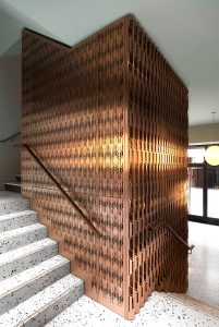 Laser-cut, V-grooved and folded PVD coloured stainless steel forming interior cladding around lift shaft. - The Gaslight Building, 29 – 35 Rathbone Street, London - Developer I.S.A Holdings - Interior architecture and design: bureau de change design office - Architects: dMFK Architects - Laser-cut PVD coloured stainless steel in custom Bronze Hairline for stairs, lift core and architectural detailing by Double Stone Steel in partnership with John Desmond Ltd. - Photography by Gilbert McCarragher