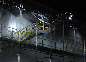 The maintenance walkway and external stair at night with the mesh screen backdrop