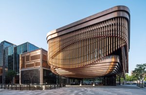 The detailed façade of the Shanghai Bund Arts and Cultural Centre in context with the more boxy style of surrounding buildings. Architectural detailing fabricated from PVD stainless steel in Rose Gold Vibration. Architects: Foster & Partners; Heatherwick Studio PVD: John Desmond Ltd, Photography by Tim Franco.