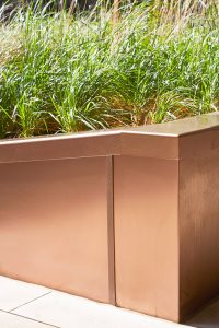 PVD coloured stainless steel in sandblasted Bronze, corner section of planter. In sunlight the Bronze PVD has a rich depth. Embassy Gardens, London, UK