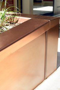 PVD coloured stainless steel in sandblasted Bronze, panel section of planter, Embassy Gardens, London, UK. This image shows how the Bronze has a warm tone in the sunshine.