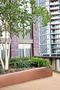 PVD coloured stainless steel in sandblasted Bronze which was specified to enhance the tones of the building materials. Embassy Gardens, London, UK.