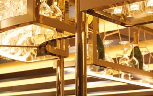 Detail of overhead bar rack in the Brasserie created from V-Grooved Champagne Mirror PVD. The Devonshire Club Hotel - Interior Design: March & White - PVD coloured stainless steel: John Desmond Ltd