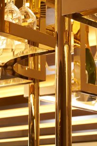 Detail of overhead bar rack in the Brasserie in Champagne Mirror PVD . The Devonshire Club Hotel Interior Design: March & White PVD coloured stainless steel: John Desmond Ltd
