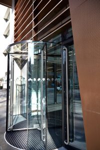 The revolving door set into the façade. 15 Fetter Lane, EC4A, London. PVD coloured stainless steel Brise soleil, canopy and column. John Desmond Ltd.