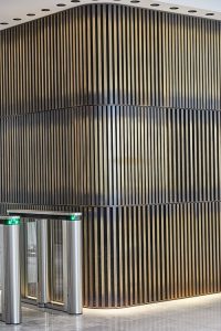 1 Broadgate Quarter, Snowden St, London, EC2A 2AW - Architects: John Robertson Architects. - Stainless Steel Canopy: John Desmond Ltd. - The rear wall clad in three rows of narrow brass bars creates a warm, welcoming backdrop to the reception area.