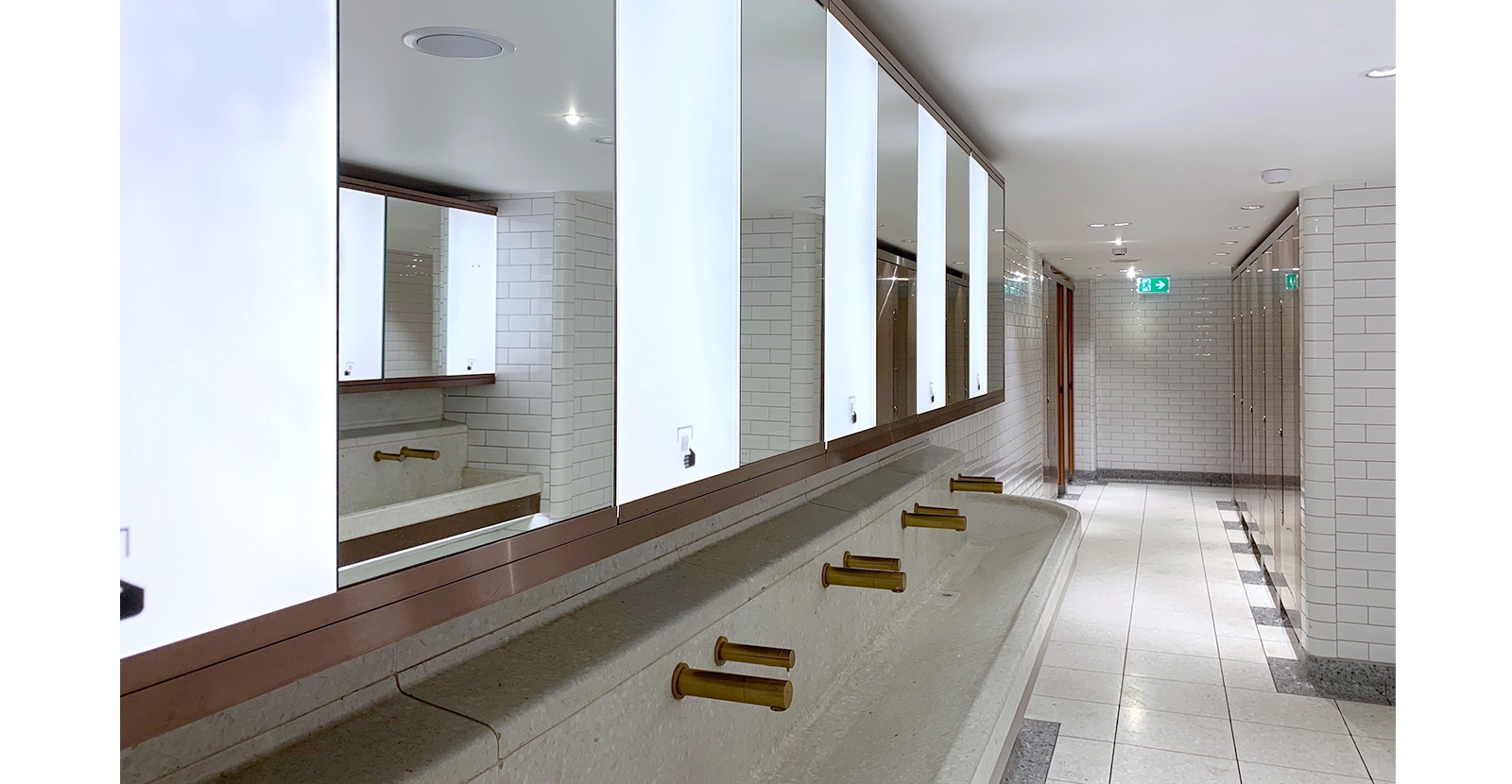 The streamlined, sleek design of the communal hand-basin, mirrors and taps. London Victoria Rail Station WC. - Architects Landolt + Brown. Fit out contractor Maxwood Washrooms.