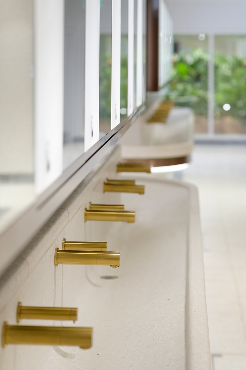Communal basin with curved perimeter and taps in PVD coloured stainless steel Bronze No 4 Brushed finish.  Project: WCs upgrade, Victoria Station, London Client: Network Rail Architects: Landolt + Brown Fitout: Maxwood Washrooms PVD coloured stainless steel by Double Stone Steel Architectural metalwork by John Desmond Ltd