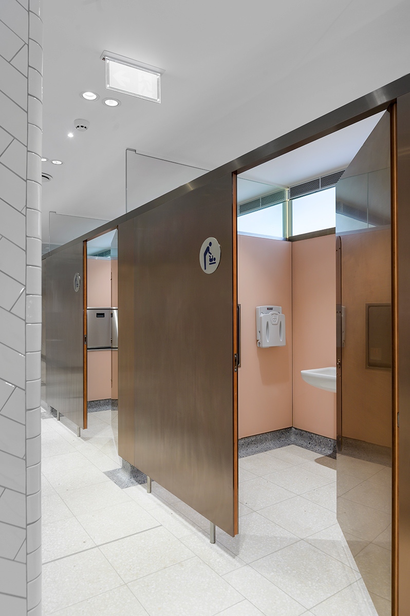 Toilet cubicles with calming colour palette interior, down-to-the- floor partition and PVD coloured stainless steel doors in Rose Gold Hairline.  Project: WCs upgrade, Victoria Station, London Client: Network Rail Architects: Landolt + Brown Fitout: Maxwood Washrooms PVD coloured stainless steel by Double Stone Steel Architectural metalwork by John Desmond Ltd