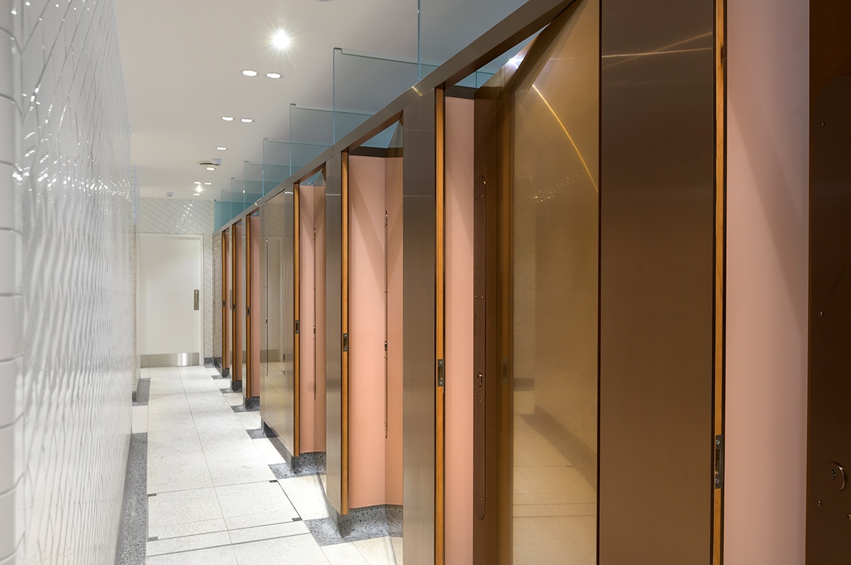 Interior of upgraded WCs Victoria Station, London with 18 mm thick glossy white brick and curved terrazzo skirting for ease of cleaning.  Client: Network Rail Architects: Landolt + Brown Fitout: Maxwood Washrooms PVD coloured stainless steel by Double Stone Steel Architectural metalwork by John Desmond Ltd