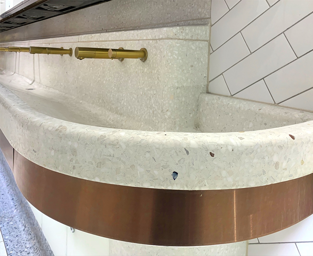 Communal basin with curved perimeter and horizontal banding in PVD coloured stainless steel Bronze No 4 Brushed finish to match taps.  Client: Network Rail Architects: Landolt + Brown Fitout: Maxwood Washrooms PVD coloured stainless steel by Double Stone Steel Architectural metalwork by John Desmond Ltd