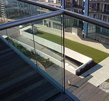 Balcony with structural, glass balustrading bonded with structural silicone to lightly glass peened (JDIF No. 66) stainless steel handrail.