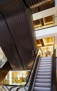 Escalators in an Art Deco palette of almond gold and nickel bronze PVD coloured stainless steel with accompanying black and white detailing. - Renovated escalator hall, Knightsbridge store, London, UK. - Architect: Make Architects - PVD coloured stainless steel trims: John Desmond Ltd
