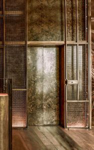 Exterior cladding panels to lift shaft in double layers of Amron Rigid Woven Architectural mesh M22-28 and I-188 in Antique Bronze. - Hide Restaurant, 85 Piccadilly, London. - Collaboration project between Hedonism Wines and Chef Ollie Dabbous - Client & Restaurateurs: Evgeny Chichvarkin and Tatiana Fokina - Interior designers: These White Walls - Architectural consultancy: Lusted Green - Staircase: Atmos Studio