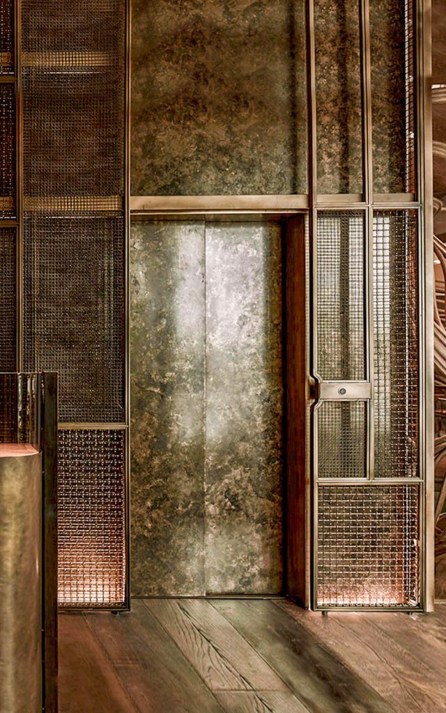 Exterior cladding panels to lift shaft in double layers of Amron Rigid Woven Architectural mesh M22-28 and I-188 in Antique Bronze. - Hide Restaurant, 85 Piccadilly, London. - Collaboration project between Hedonism Wines and Chef Ollie Dabbous - Client & Restaurateurs: Evgeny Chichvarkin and Tatiana Fokina - Interior designers: These White Walls - Architectural consultancy: Lusted Green - Staircase: Atmos Studio