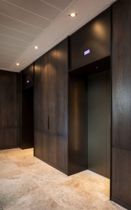 Elevator lobby with door skins, overhead panel and architrave in dark bronze electro-zinc coated V-Grooved stainless steel. - Fenman House, Apartment Building, 9 Handyside St, King’s Cross, London N1C 4AY. - Building design: Maccreanor Lavington Architects - Interiors: Johnson Naylor Architects - Developer: Argent - Manufacture: Bluecoat Engineerinng - Fabrication, V-Grooving and folding of stainless steel: John Desmond Ltd.