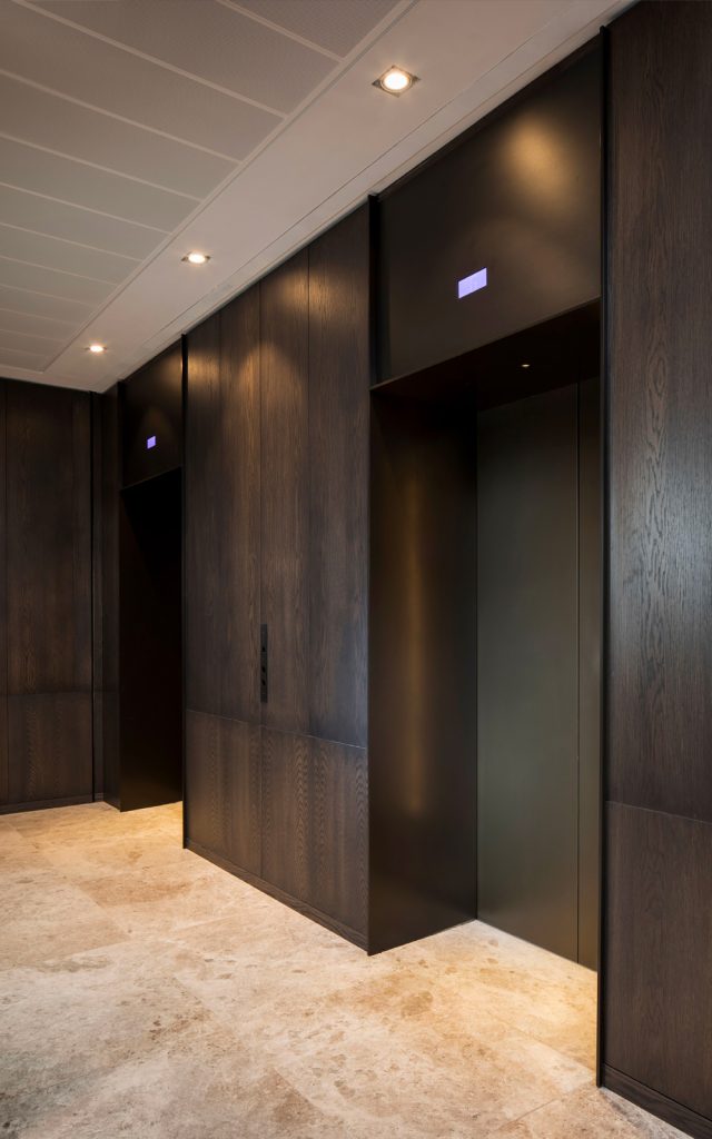 Elevator lobby with door skins, overhead panel and architrave in V-Grooved PVD coloured stainless steel Chocolate Vibration. - Fenman House, Apartment Building, 9 Handyside St, King’s Cross, London N1C 4AY. - Building design: Maccreanor Lavington Architects - Interiors: Johnson Naylor Architects - Developer: Argent - Fabrication, V-Grooving and folding of stainless steel: John Desmond Ltd.