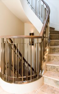 Helical staircase in PVD coloured stainless steel in Almond Gold with stained oak handrail. - Main helical staircase to 54 Bedford Gardens, Notting Hill, London, UK - Client and main contractor, Bancroft Heath - Architect: Nash Baker - Interior Designer: Desalles Flint - Architectural metalworks and PVD coated coloured stainless steel: John Desmond Ltd.