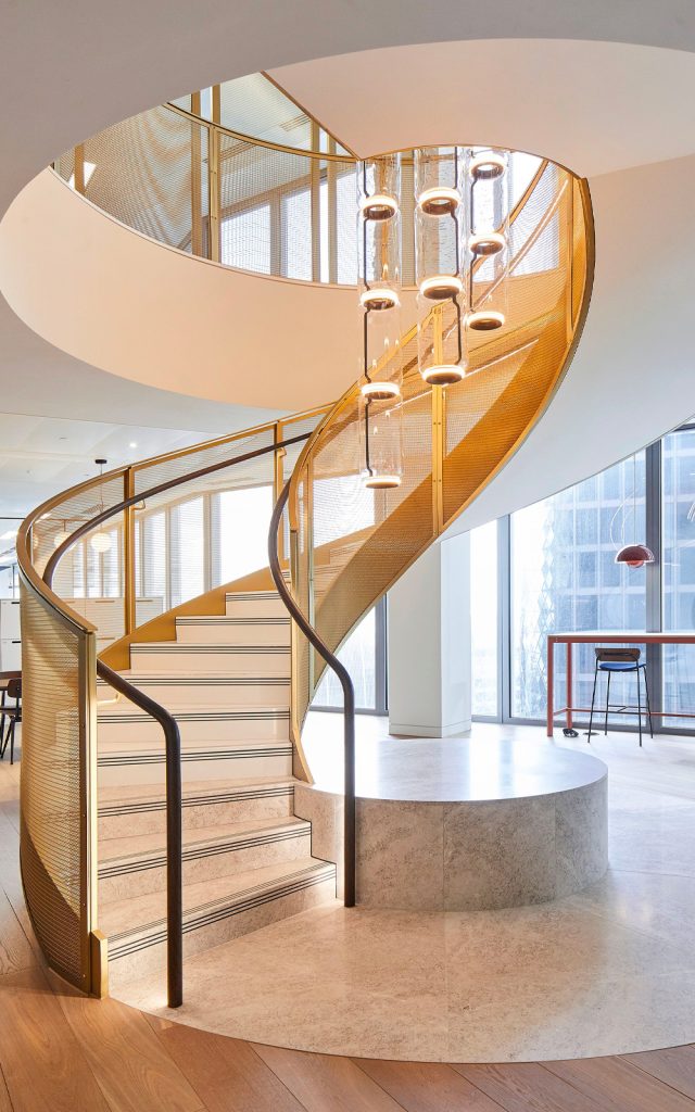 Showing circular staircase gallery balustrading and floor and ceiling mounted space dividers in JDL Amron PVD Architectural Mesh IPZ-56 in Champagne with solid framing also in PVD coloured stainless steel in Champagne. - Office premises, 22 Bishopsgate, London - Fit out of one and a half floors on the 16th and 17th floors of this 62-storey building. - Client: THB Group Insurance - Architect: T.P.Bennett - Key contractor: James Engineering - Mesh product: JDL Amron PVD Architectural mesh