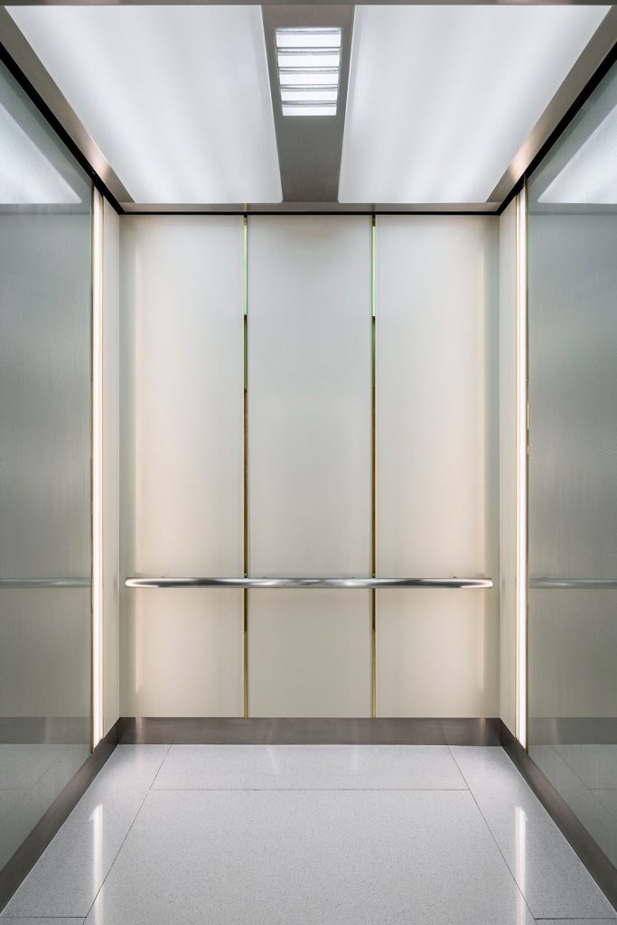 V-Grooved and folded PVD coloured stainless steel sheet forms the interior panelling, vertical trim, frieze and kick-plate for elevator cab.
