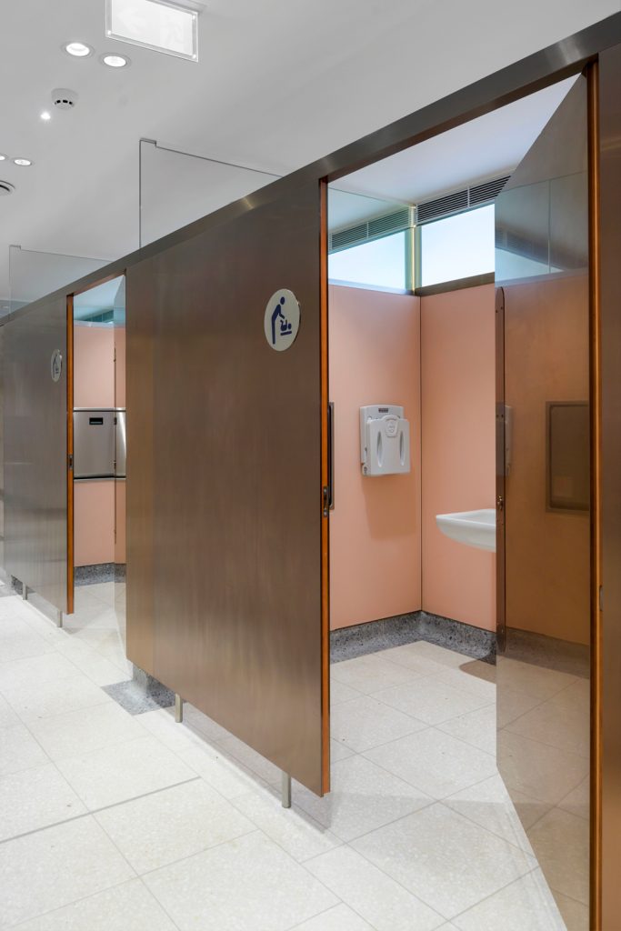 PVD coloured stainless steel is V-grooved and folded to form cladding to cubicle doors and partitioning, appearing as solid material.